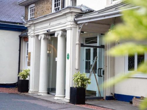 a white house with white columns and a door at Mercure Thurrock Stifford Hall in Grays Thurrock