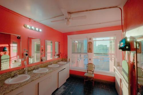 a red bathroom with three sinks and a window at California Dreams Hostel - Downtown in San Diego