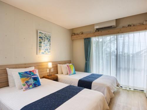 a hotel room with two beds and a window at Yomitan Condhotel ND in Yomitan