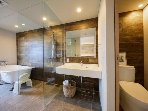 a bathroom with a tub and a sink and a mirror at Yomitan Condhotel ND in Yomitan