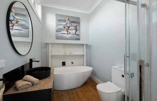 a bathroom with a large white tub and a mirror at Character Villa Oasis - Pool & Beach in Athenree