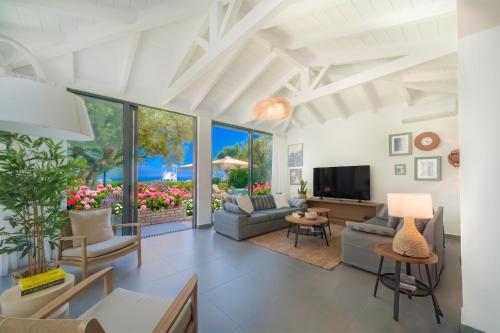 a living room filled with furniture and a flat screen tv at Barbati Beachfront - Pool Villa in Barbati