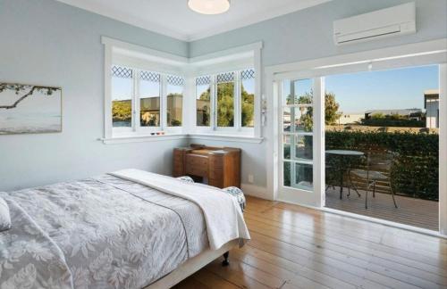 a bedroom with a bed and a balcony with a table at Character Villa Oasis - Pool & Beach in Athenree
