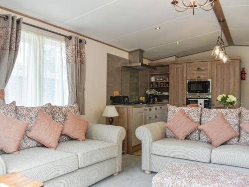 a living room with two couches and a kitchen at Deer Glade Lodge in Landford