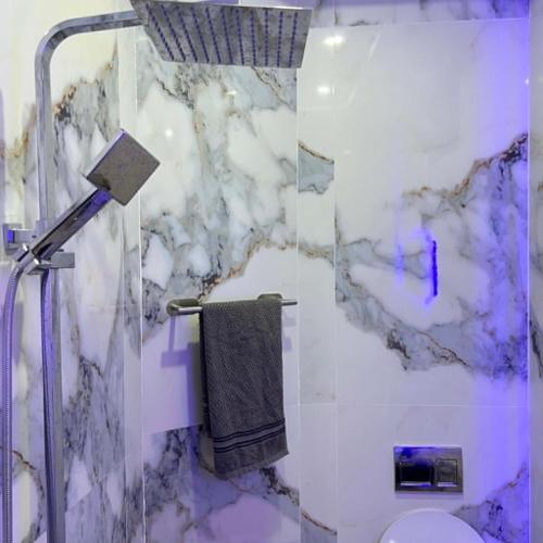 a marble bathroom with a shower and a toilet at Villa Jenna in Kelibia