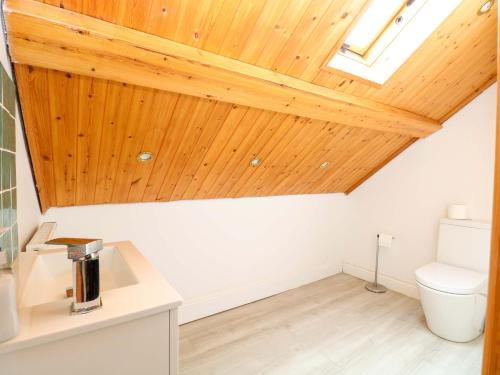a bathroom with a toilet and a wooden ceiling at Tilly's Retreat in Hunstanton