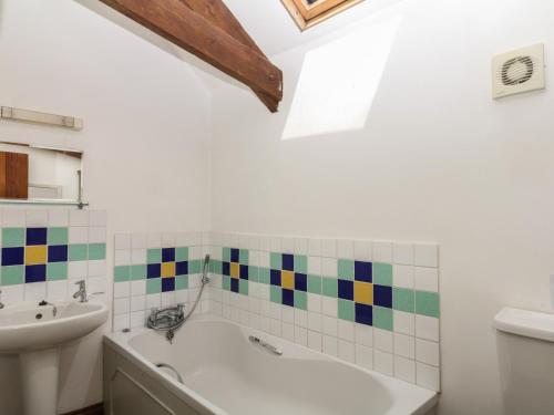 a bathroom with a bath tub and a sink at Fixit Cottage in Kingsbridge