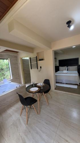 a living room with a table and chairs and a bed at Green Valley Hydro Suite - Monte Verde-MG in Camanducaia