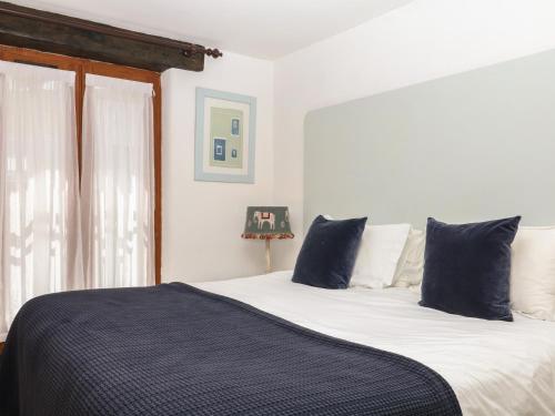 a bedroom with a bed with blue pillows and a window at Mixit Cottage in Kingsbridge