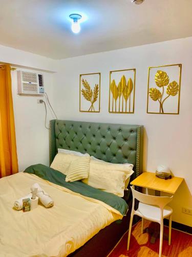 a bedroom with a bed with a green headboard and a desk at Casa Bonita Davao in Davao City