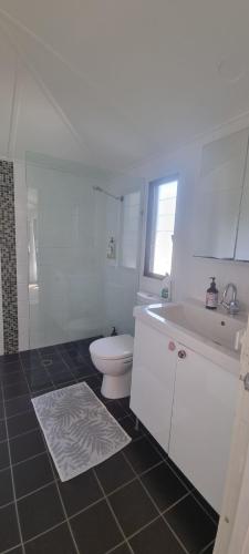 a white bathroom with a toilet and a sink at Ocean High in Yamba