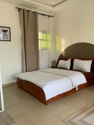 a bedroom with a large bed with a wooden headboard at Residence Emilienne in Cotonou