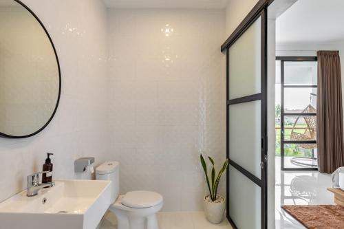 a bathroom with a sink and a toilet and a mirror at Villa Alba by Orivista, Rice Field View in Dalung