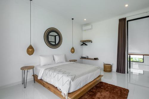 a white bedroom with a bed and a mirror at Villa Alba by Orivista, Rice Field View in Dalung