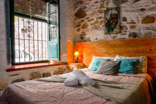 a bed in a bedroom with a stone wall at Posada San Gabriel in Colonia del Sacramento