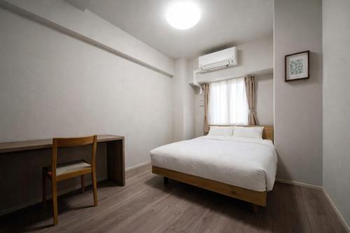 a bedroom with a bed and a chair and a window at Formosa Hills in Kumamoto