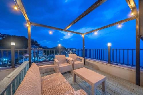 a balcony with chairs and tables at night at Samcheok Pureun Bada Pension in Samcheok