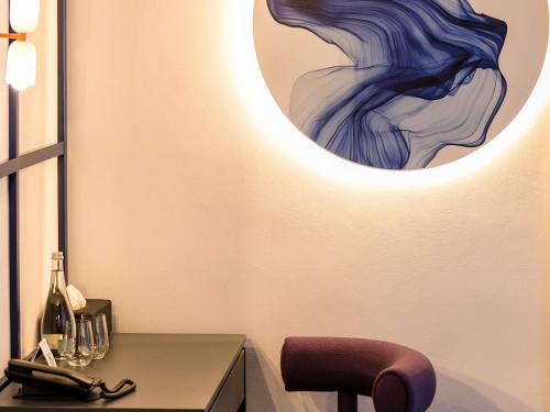a table with a chair and a painting on the wall at Mercure Bucharest Cantemir in Bucharest