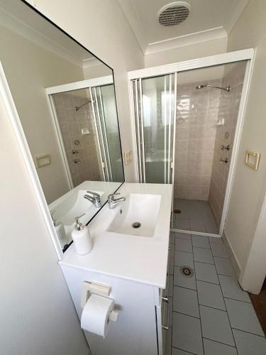 a white bathroom with a sink and a shower at Baybreeze - Bring your own linen in South West Rocks