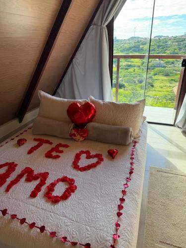a bed with red roses on it with a window at Chale Gameleiras in Monte das Gameleiras