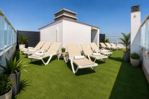 a patio with chaise lounge chairs and grass at Hôtel le Canetois in Canet-en-Roussillon