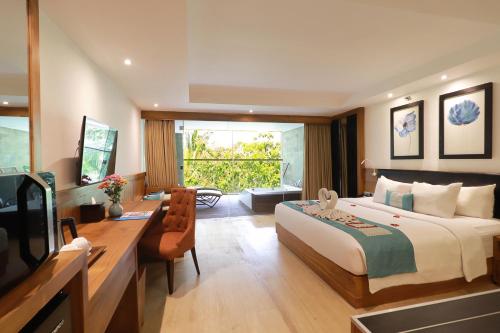 a bedroom with a bed and a desk and a television at de Vins Sky Hotel Seminyak in Seminyak