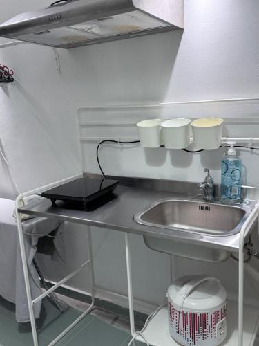 a kitchen counter with a sink and cups on a shelf at Dino House in Taiping