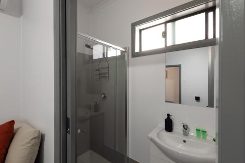 a white bathroom with a sink and a shower at Broken Hill Tourist Lodge in Broken Hill
