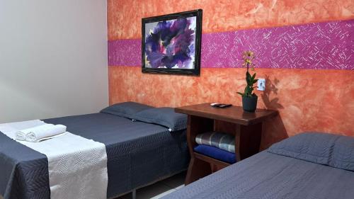 a room with two beds and a table with a plant on it at Pousada Moaçara in Estivado
