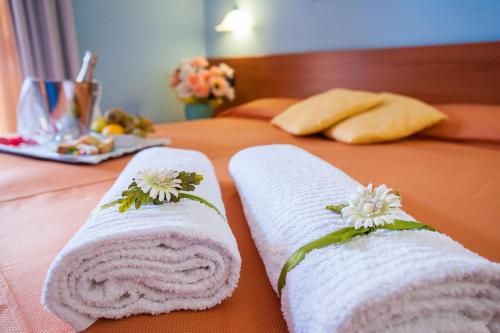 Dos toallas en una cama con flores. en Hotel Bacco, en Ascea