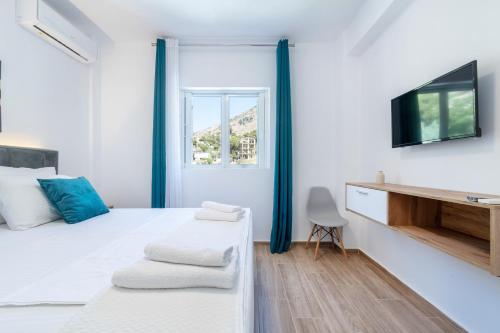 a white bedroom with a tv and a bed at Villa Virginia in Sarandë