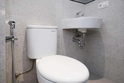 a bathroom with a white toilet and a sink at SANS Vibes Surya in Stasiun Tawang