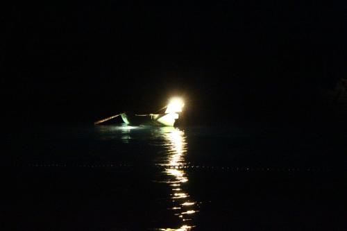 una barca con luce sull'acqua di notte di Re Merlo a Marina di Camerota