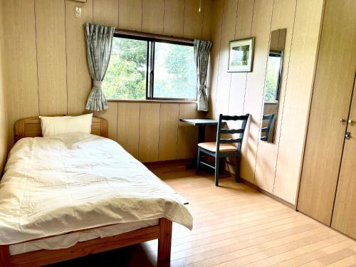 a bedroom with a bed and a desk and a window at 田園の宿 in Takehanachō