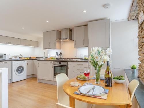 a kitchen with a wooden table with flowers on it at Dayan Cottage in Fowey