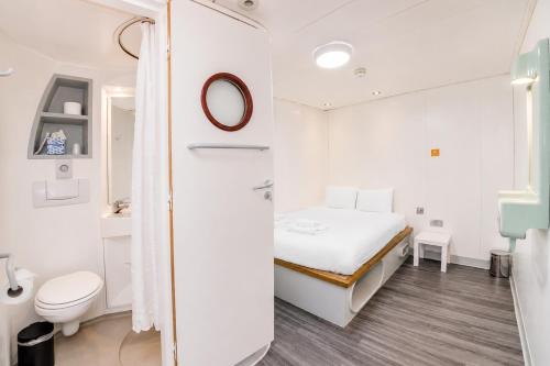 a small white room with a bed and a toilet at Citi Hotel London Heathrow in Hillingdon