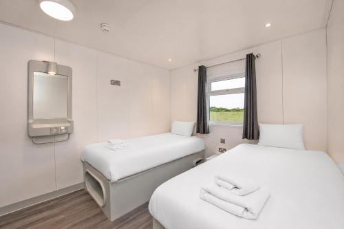 two beds in a room with a tv and a mirror at Citi Hotel London Heathrow in Hillingdon
