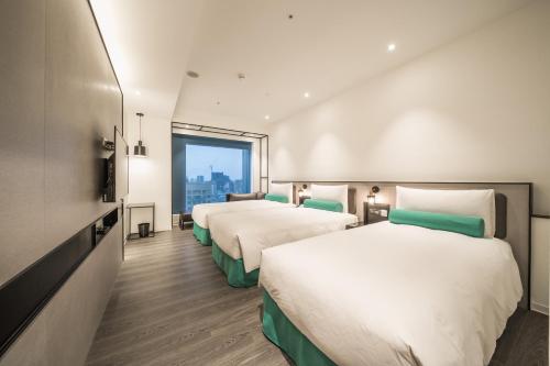 a hotel room with two beds and a window at Caesar Metro Taipei in Taipei