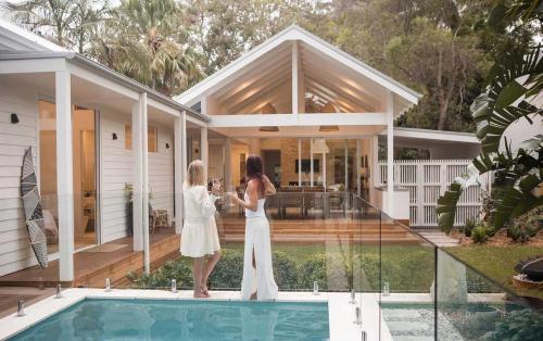 two women standing on the balcony of a house at Moso House Pearl Beach in Pearl Beach