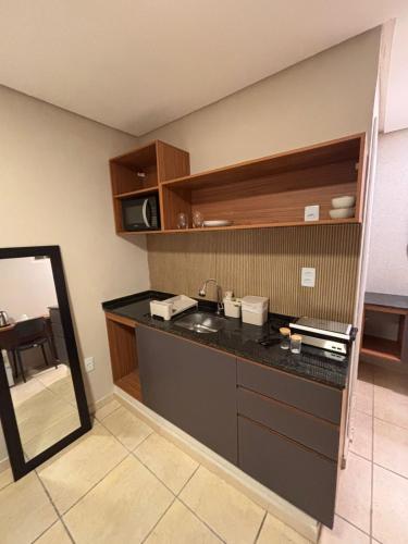 a kitchen with a counter with a sink and a mirror at Blume Suítes Premium Orla in Petrolina