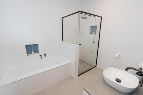 a white bathroom with a sink and a bath tub at Quampi House with Best Ocean View in Point Lookout