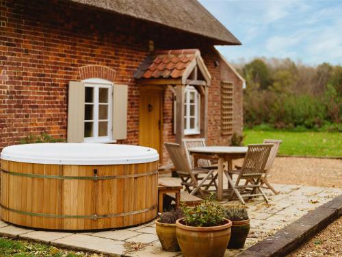 a large wooden barrel sitting next to a table and chairs at New Lane Cottage in Worstead