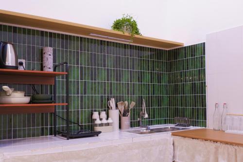 a kitchen with green tiles on the wall at Ni Nớ Home in Hue