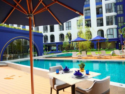 a table with chairs and an umbrella next to a pool at Above Element Bangtao Phuket by Arthouse Collection in Laguna Phuket