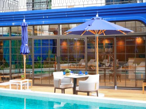 a table with an umbrella next to a swimming pool at Above Element Bangtao Phuket by Arthouse Collection in Laguna Phuket
