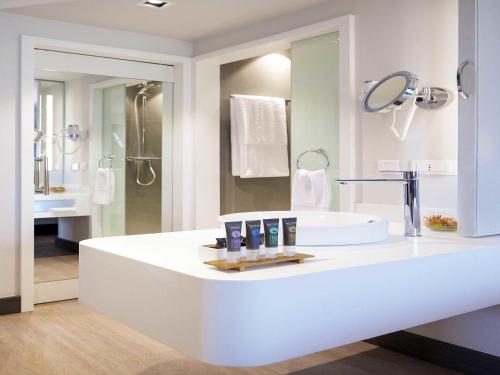 a white bathroom with a sink and a mirror at Novotel Cotonou Orisha in Cotonou