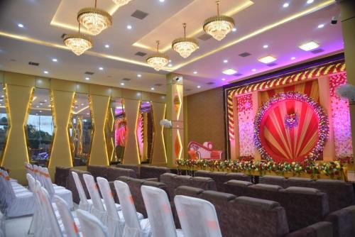 a banquet hall with white chairs and a stage at Lagna Mahal in Birnon