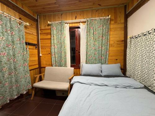 a bedroom with two beds and a chair and a window at Mây inn' Cầu Đất - Homestay in Xuân Trường