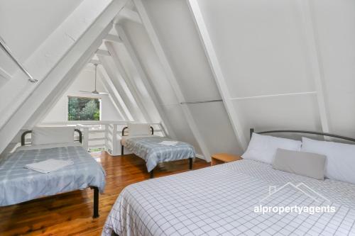 a attic bedroom with two beds and a window at The A-Frame in Halls Gap
