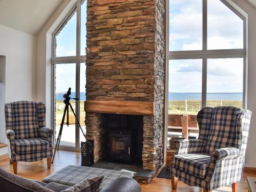 a living room with two chairs and a stone fireplace at Ryka Lodge in Back